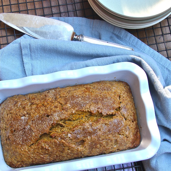 A loaf pan of pumpkin bread on a cooling rack.