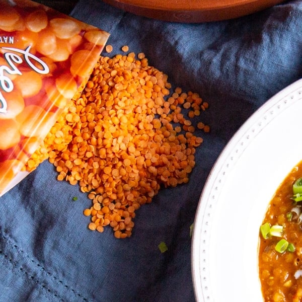 Close up shot of red lentils, also called orange lentils on a blue napkin.