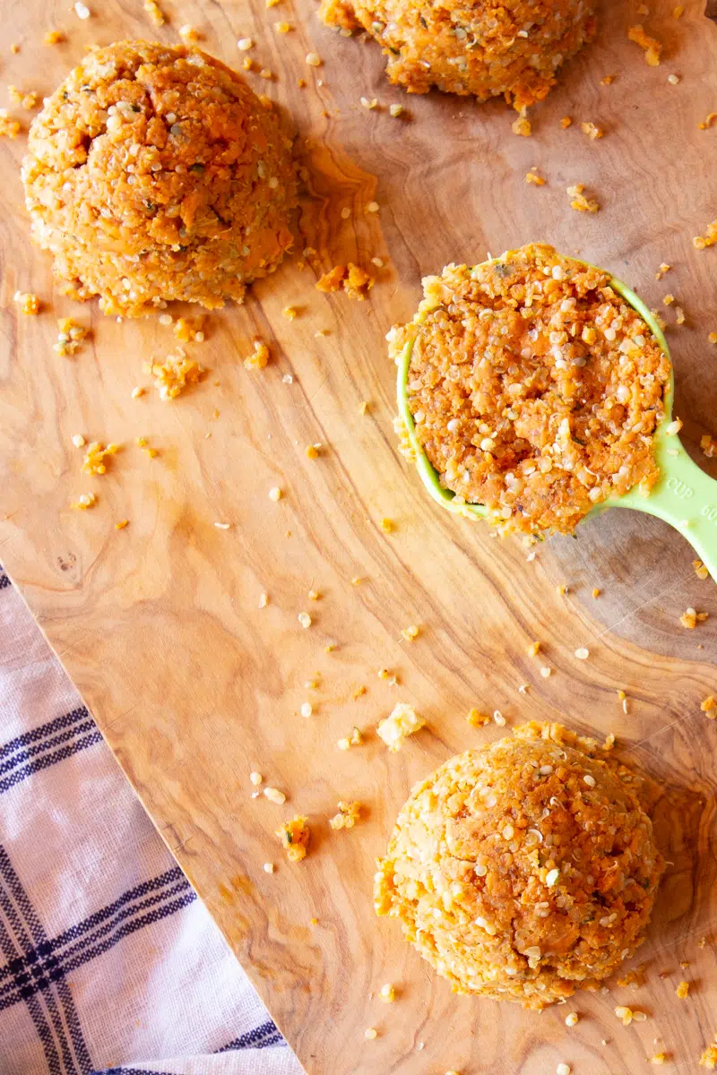 Sweet potato cakes scooped into a ¼ cup measuring cup, and dumped out onto a work space.