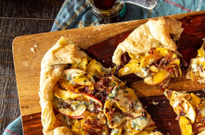 This addictive delicata squash and apple galette appetizer is quick to prep, and perfect for any party. Smear puff pastry with fig jam, layer it with squash, apples and caramelized onion, and bake. Drizzle with honey and add blue cheese crumbles before serving.
