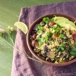 Quinoa and millet salad made with black beans, slices of avocado, grapes and cilantro.