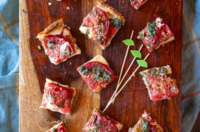 This Tomato Caprese Tart is easy to make with fresh peak season tomatoes, mozzarella cheese, and a pesto - all tucked into a tart shell. Use it for an appetizer, side dish or vegetarian dinner.