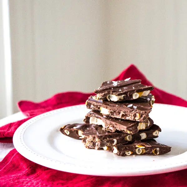Pieces of Chocolate and Pretzel Bark with Sea Salt stacked on a plate.