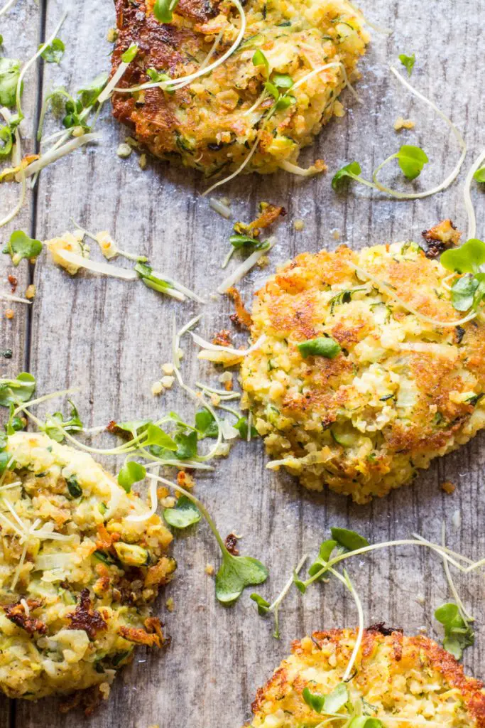 Zucchini fritters on a serving board, topped with sprouts.