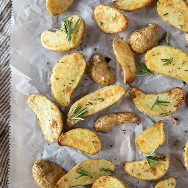 Fingerling potatoes that have been seasoned and cooked in the air fryer. A little rosemary is scattered on top.