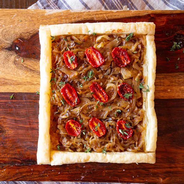 Puff pastry tart filled with caramelized onions and mushrooms, topped with roasted tomatoes.