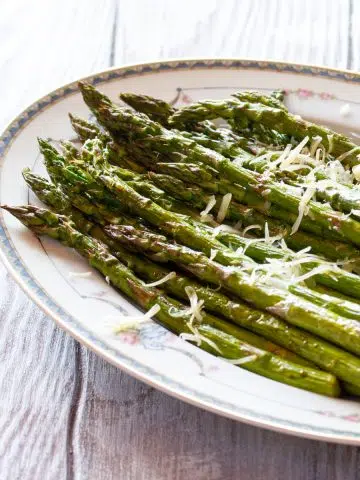 A plate of asparagus roasted in the air fryer, topped with a little Parmesan cheese.