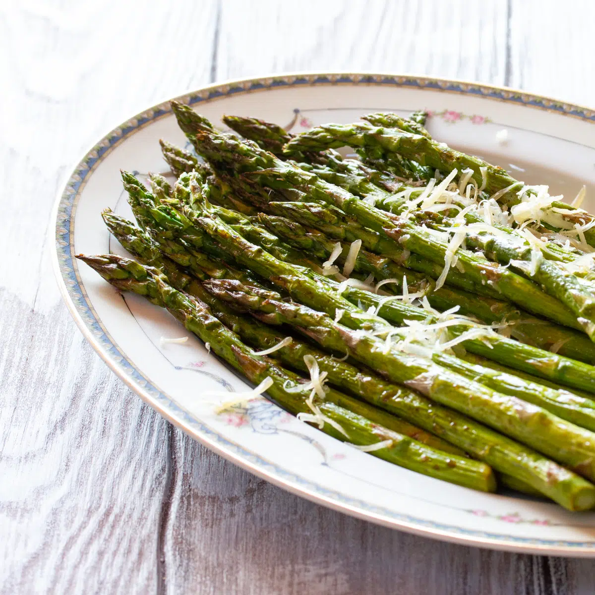 A plate of asparagus roasted in the air fryer, topped with a little Parmesan cheese.