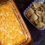 Refried beans mixed with cream cheese, sour cream and taco seasoning, and topped with cheese. A bowl of chips on the side.