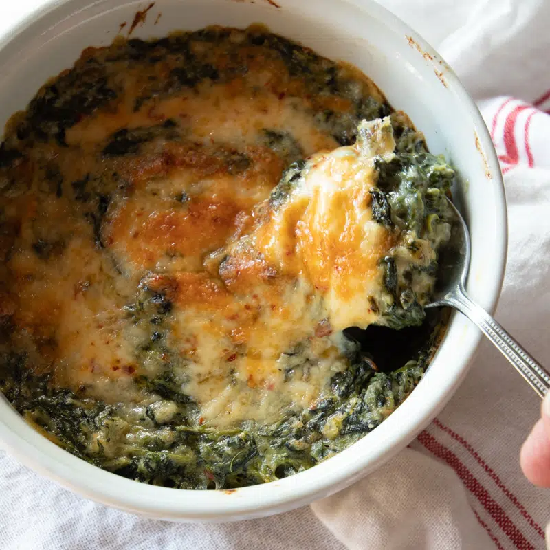 Creamed spinach topped with gooey cheese in a large dish.