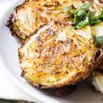 Thick crispy cabbage slabs arranged like steaks on a plate.