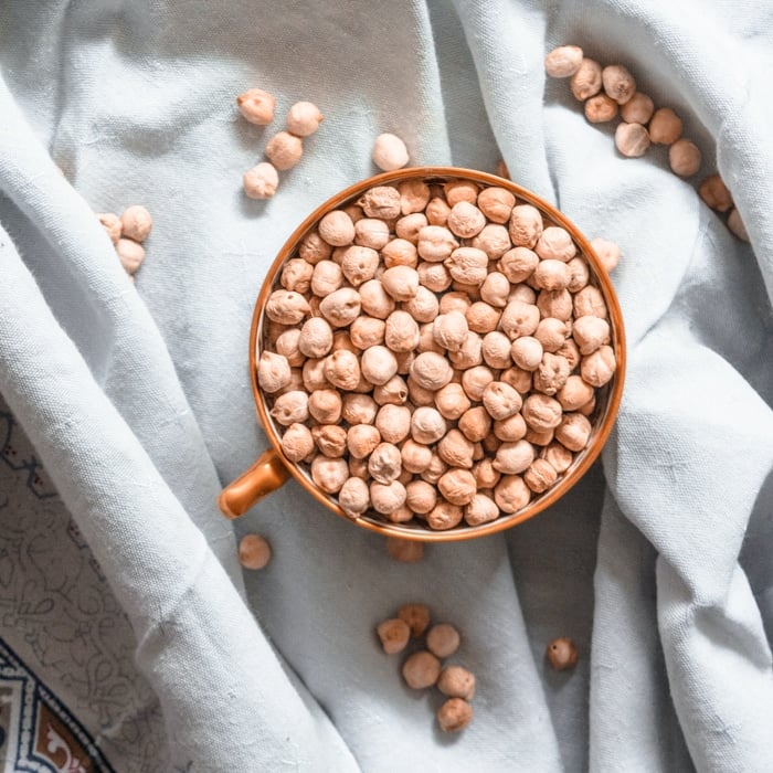 A cup filled with dried chickpeas.
