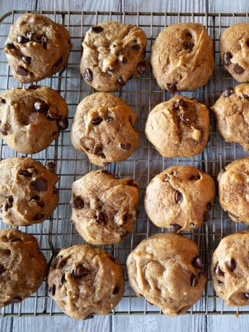 Soft pumpkin cookies with chocolate chips on a cooling tray.