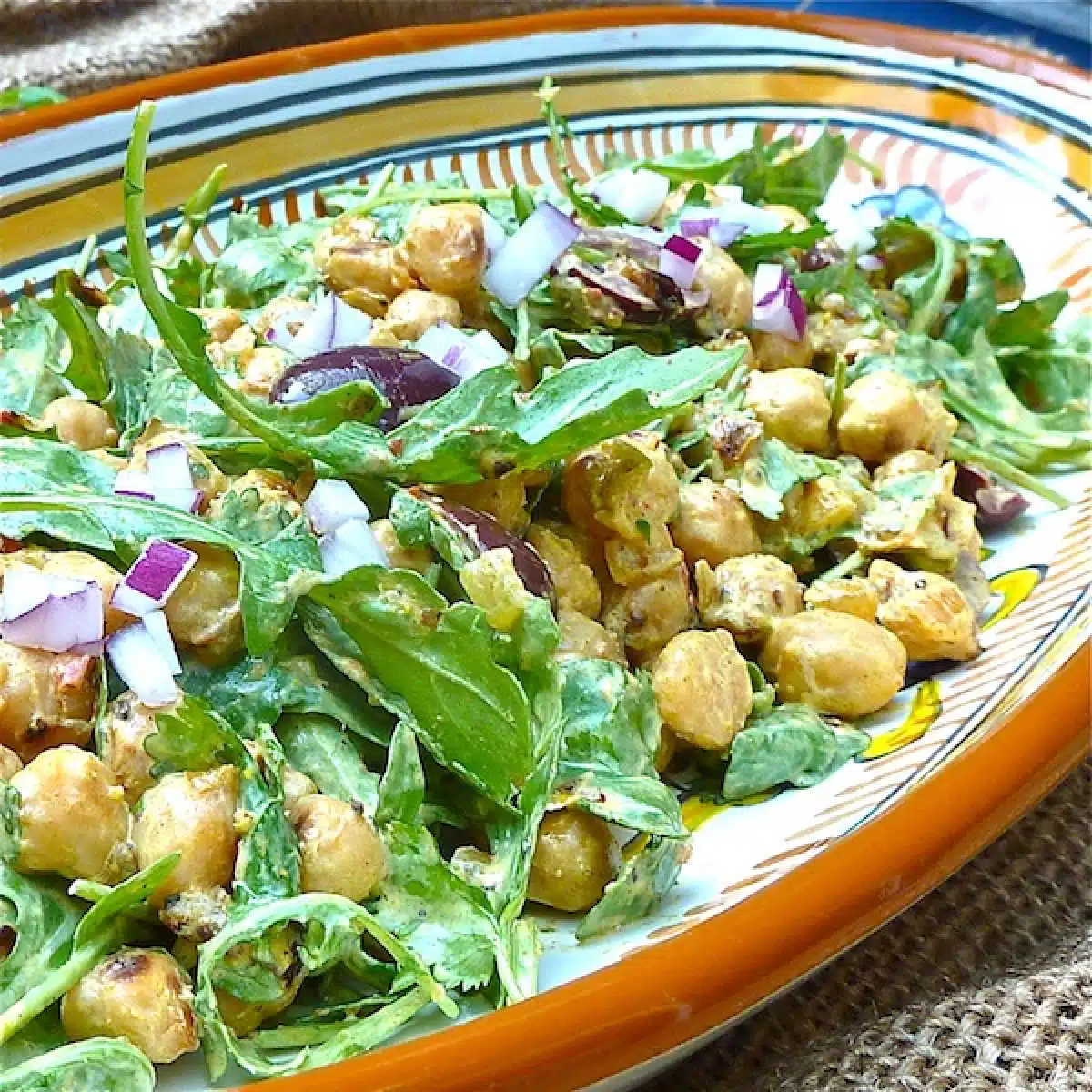 Chickpeas tossed in a yogurt curry dressing with arugula, topped with minced red onion.