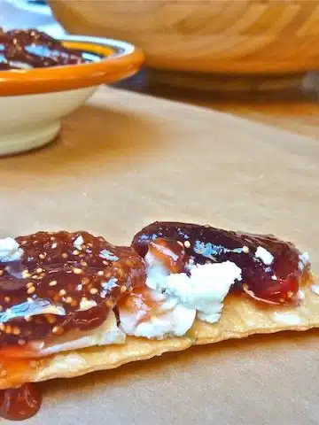 Fig jam on top of cheese and crackers on a table.