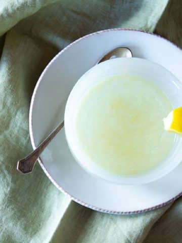 Top view of honey lemon ginger tea, with a lemon wedge on the cup.