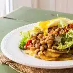 A plate of roasted potatoes topped with black-eyed peas, frisée and an egg.