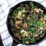 A skillet of a vegan Swiss chard sauté with quinoa, lemon, capers and olives.