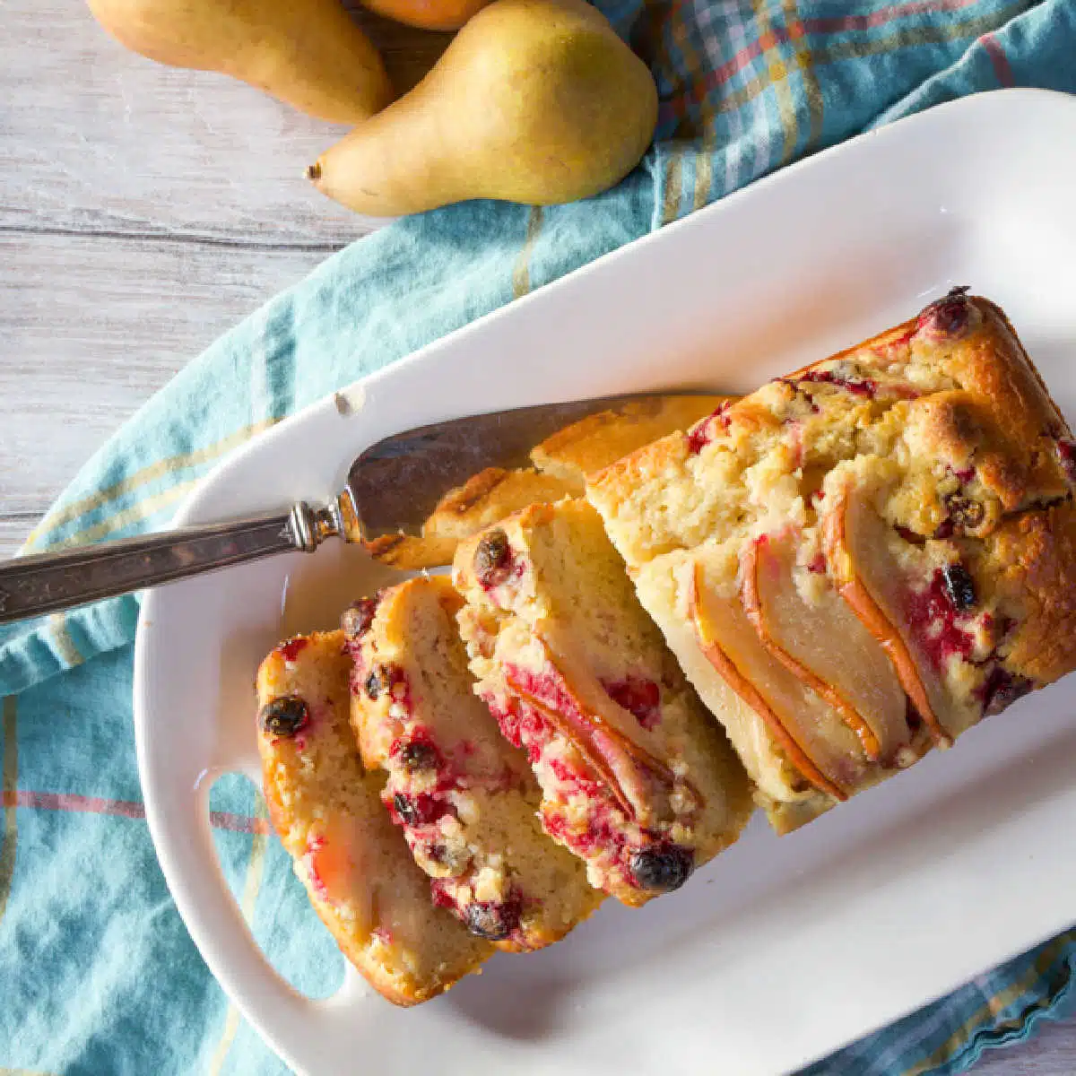 A serving platter of yogurt cake with pears, cranberries and chocolate chips.
