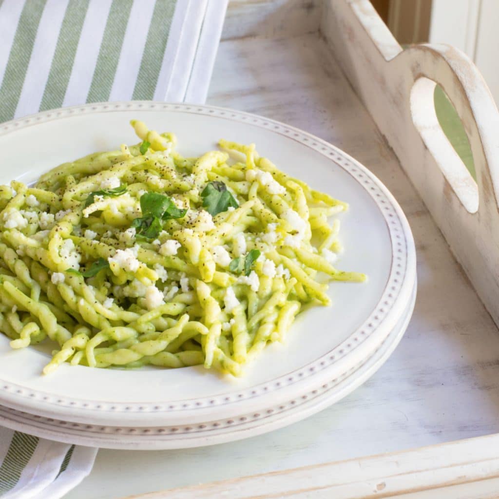 A plate of trofie twisted pasta tossed in a creamy poblano sauce topped with queso fresco cheese.