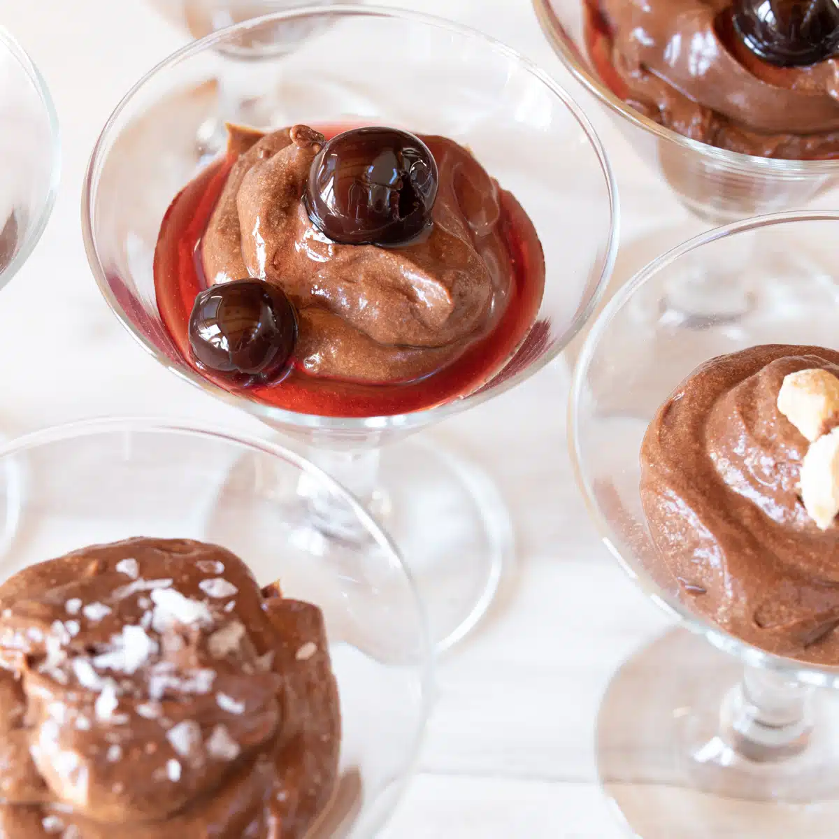 Small glasses filled with Bailey's Chocolate Mousse with different toppings: cherries, nuts, and salt.