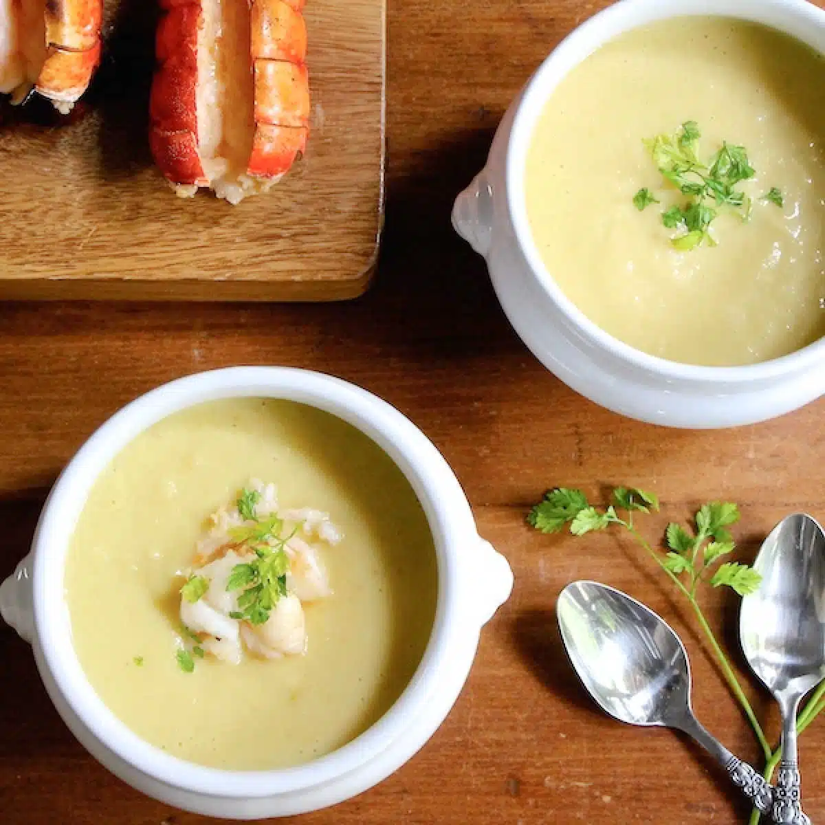 Two bowls of celery root bisque, with one topped with lumps of lobster.