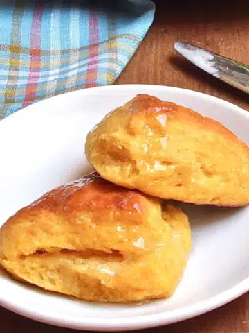A plate with 2 sweet potato biscuits basted with melted butter.