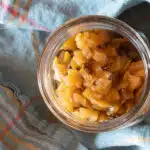 A view down into a jar filled with apple chutney cooked with raisins.