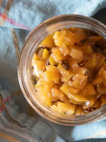 A view down into a jar filled with apple chutney cooked with raisins.