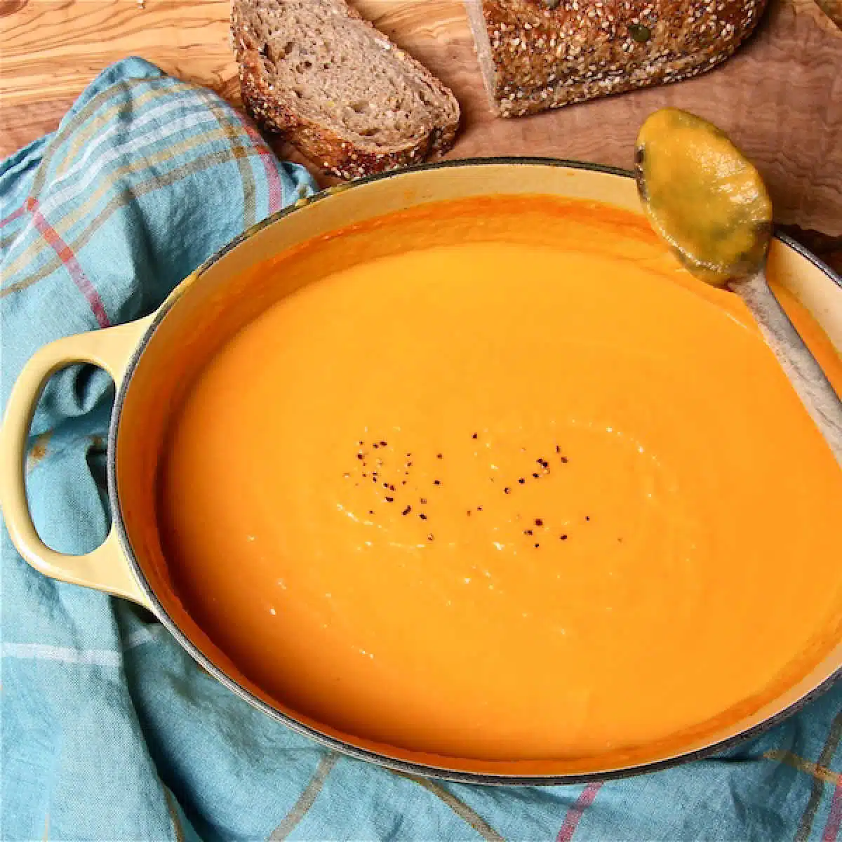 A big pot of silky sweet potato and carrot soup, with a few slices of bread on the side.