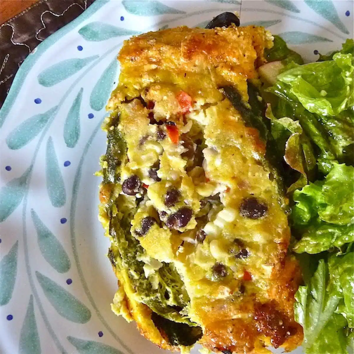 A serving of chile rellenos breakfast casserole on a plate with a salad.