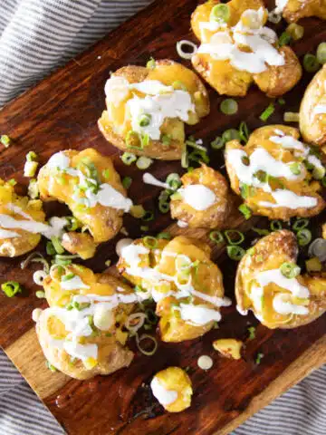 Roasted smashed potatoes topped with melted cheese, green onions, and Mexican crema.