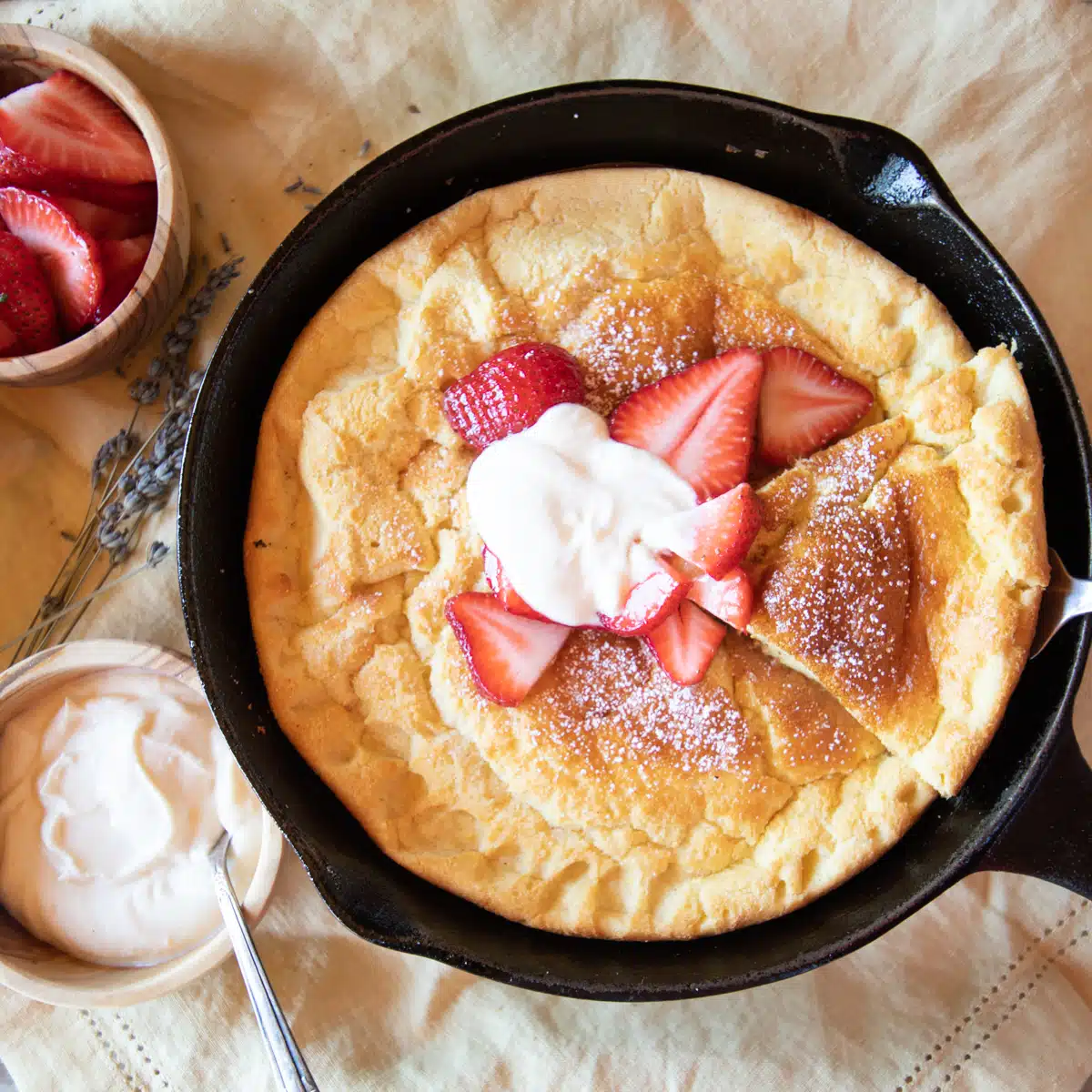 Soufflé style German pancake, cut, and topped with strawberries and whipped ricotta cheese.