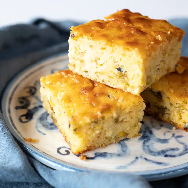 Newly cut cornbread pieces stacked on a plate.