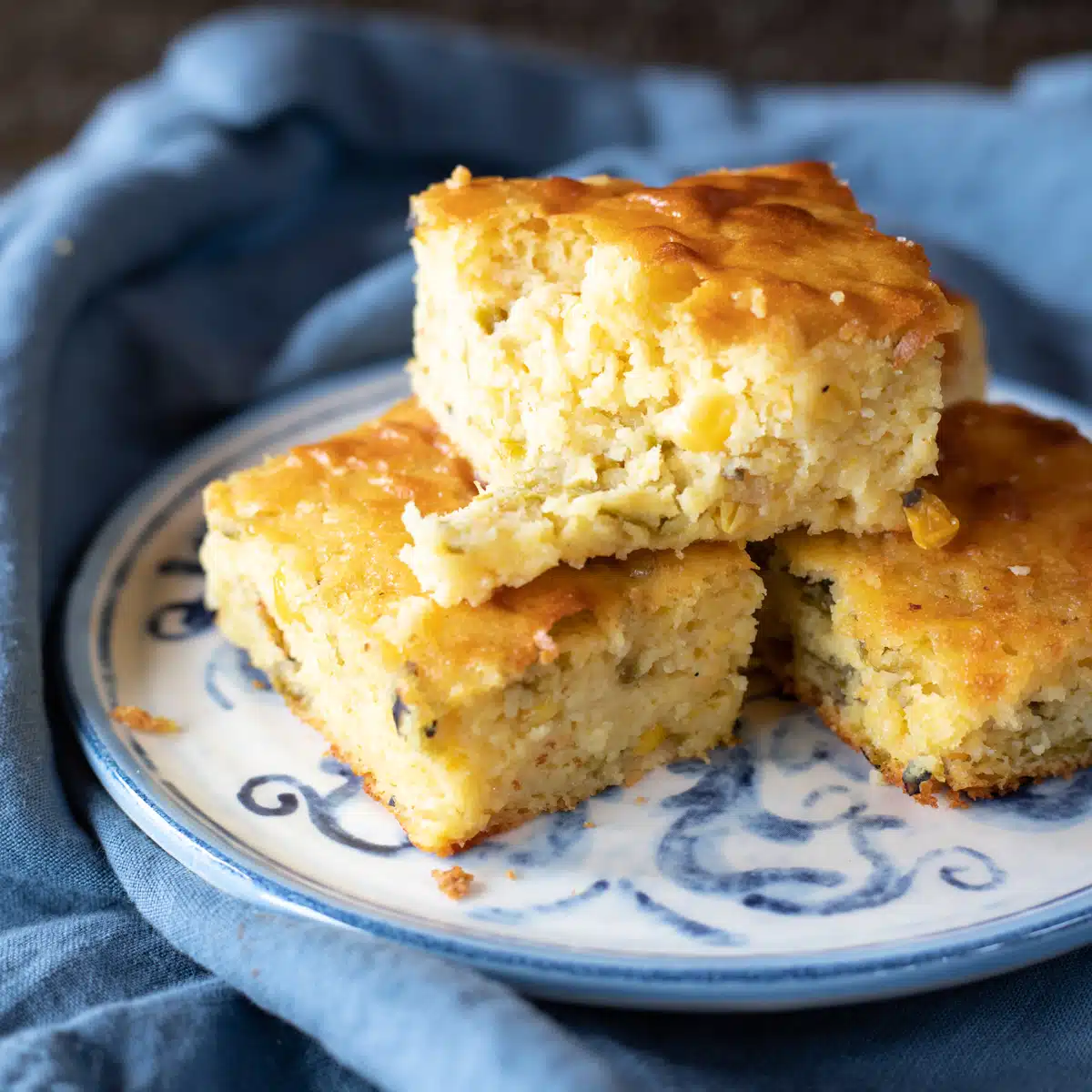 Three pieces of mexican cornbread stacked on top of each other, with one broken up a little.