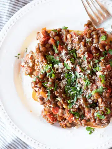 Lentil sloppy joes on a slice of toasted roll, topped with chopped parsley.