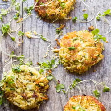 Zucchini fritters on a serving board with sprouts scattered over them.