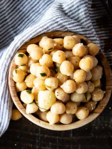 A wooden bowl of cooked chickpeas.