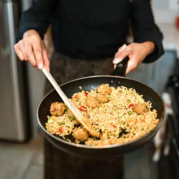 A pan of fried rice being held by a woman.