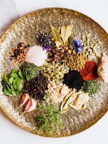 A gold plate filled with various herbs and spices.