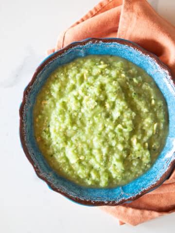 A bowl of tomatillo green-chili salsa verde with a napkin.
