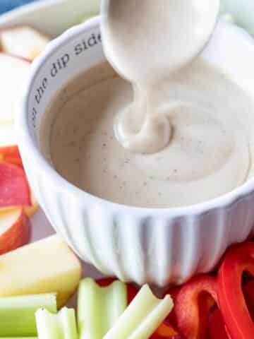 Maple tahini Sauce poured into a dipping cup with veggies.