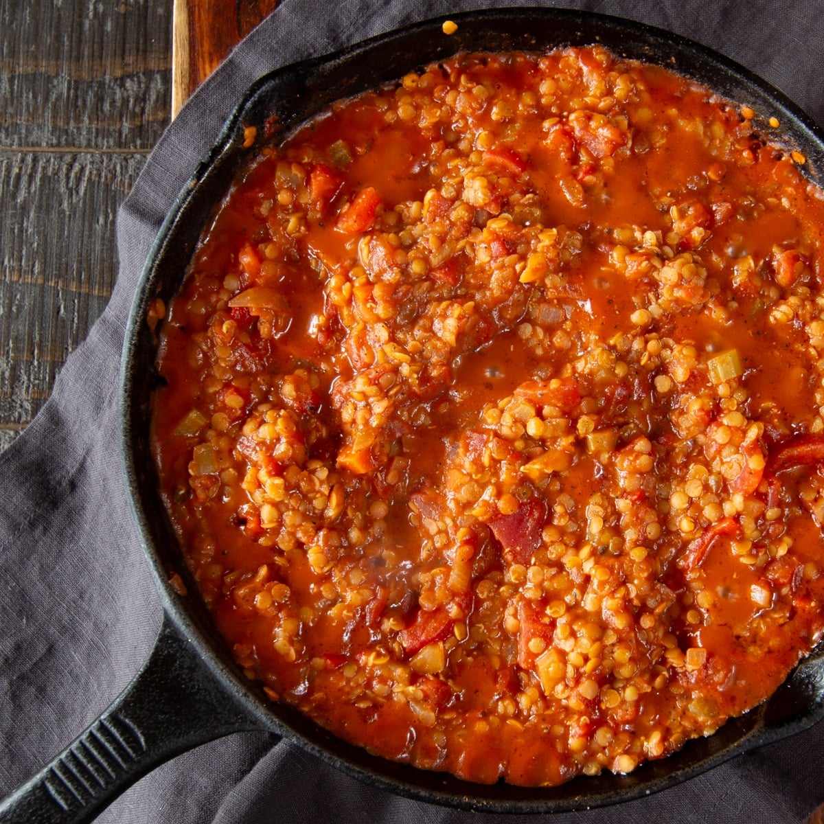 A cast iron skillet filled with red lentil bolognese sauce.