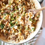 Closeup of a pan of creamy mushroom stroganoff topped with parsley with a wooden spoon.