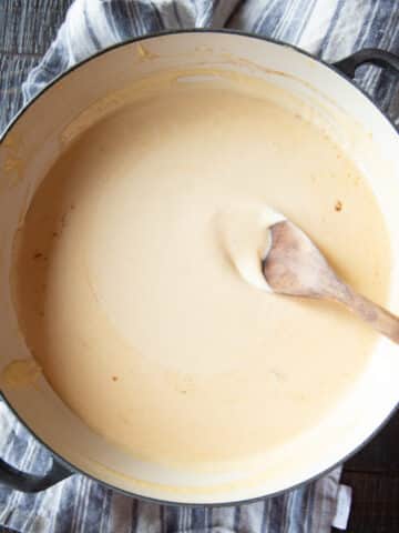 A wide-mouthed pan of Stouffer's Welsh Rarebit cheese sauce with a wooden spoon.